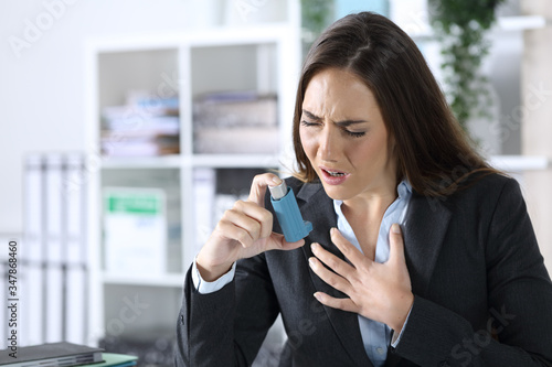 Executive holding inhaler with asthma attack at office photo