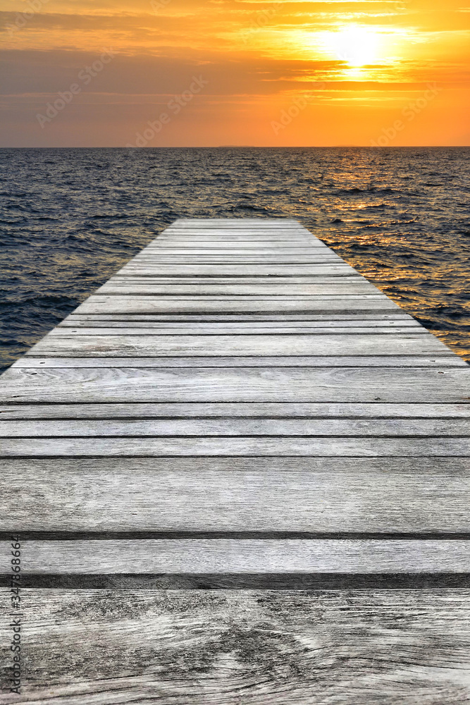 Sunset at sea and old wooden bridgeมPerspective view of wooden pier on the sea at sunset with perfectly specular reflection,wooden retro deck and sunrise or sunset sky/ Summer holidays background. Sunset at sea and old wooden bridgeมPerspective view of wooden pier on the sea at sunset with perfectly specular reflection,wooden retro deck and sunrise or sunset sky/ Summer holidays background.