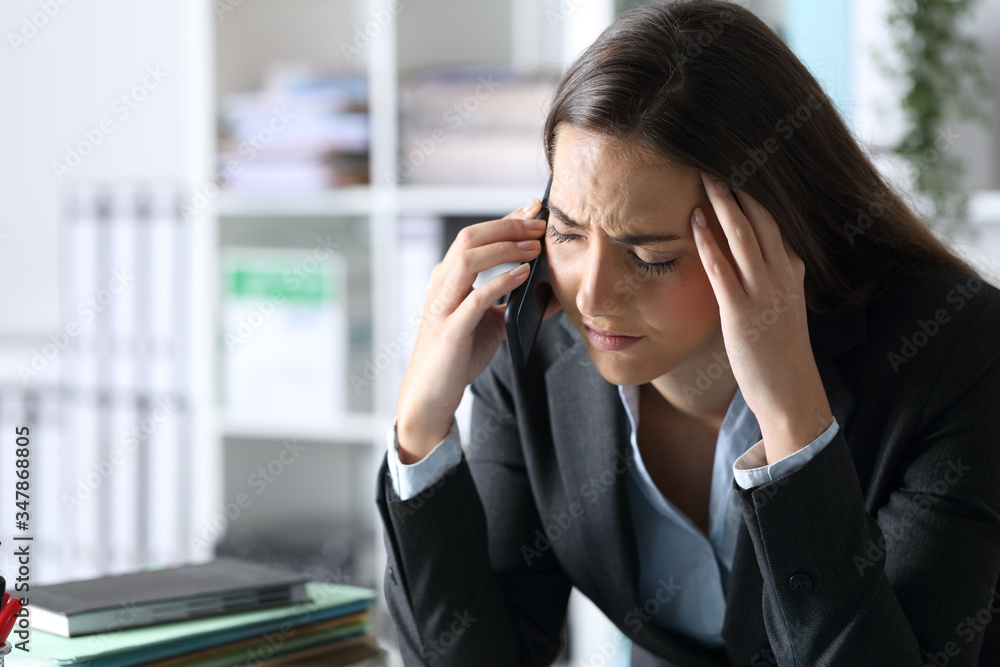 Sad executive calling on phone at office desk Sad executive calling on phone at office desk