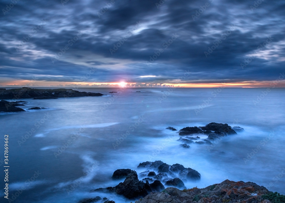 Obraz premium Sunset time at the Mendocino Headlands State Park, Northern California, USA, featuring predominantly blue colors and some clouds with lots of copy space and lens flare