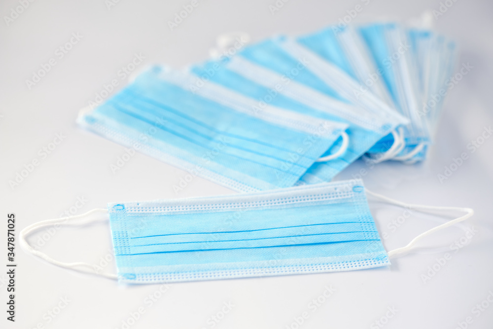 A stack of new unused disposable face masks lying on white background. Seen in Germany in May during corona crisis. A stack of new unused disposable face masks lying on white background. Seen in Germany in May during corona crisis.
