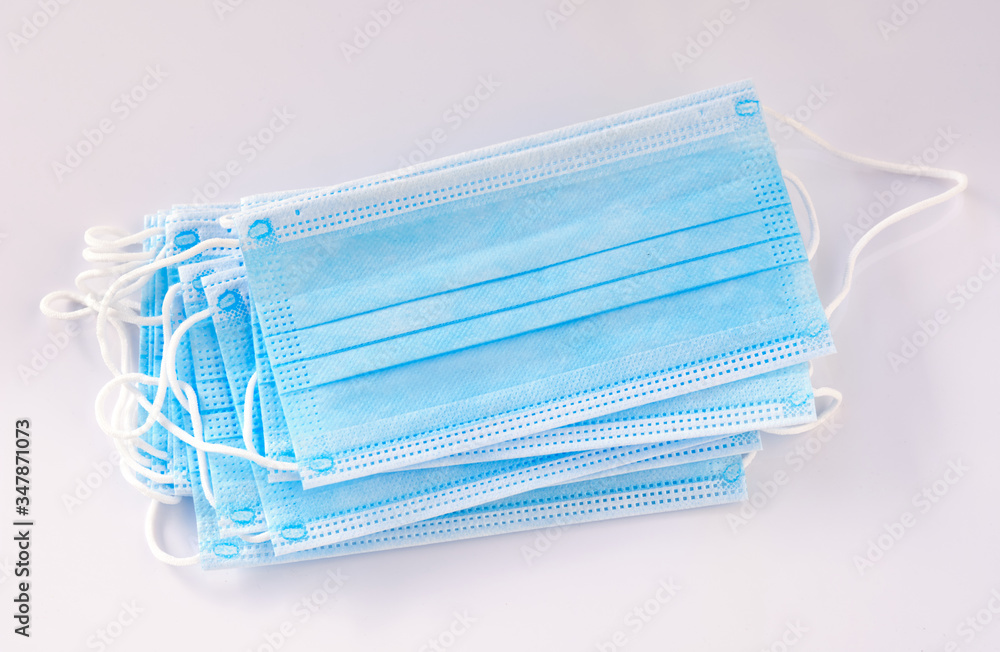 A stack of new unused disposable face masks lying on white background. Seen in Germany in May during corona crisis. A stack of new unused disposable face masks lying on white background. Seen in Germany in May during corona crisis.