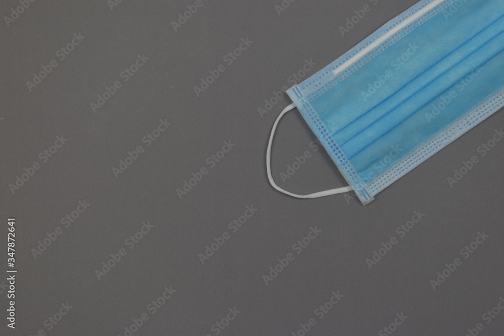 Blue medical mask on grey background. Face mask protection against pollution, virus, flu and coronavirus covid-19. Blue medical mask on grey background. Face mask protection against pollution, virus, flu and coronavirus covid-19.