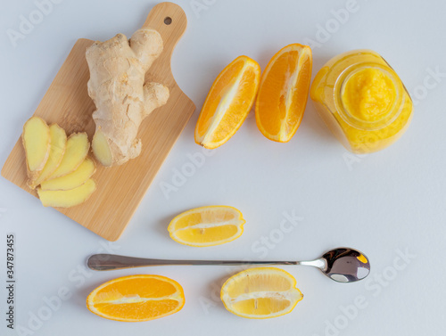 Jar of jam from orange, lemon with honey and ginger and slices of lemon and orange on a light background 