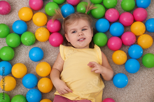 Cute little child playing with balls on floor, top view