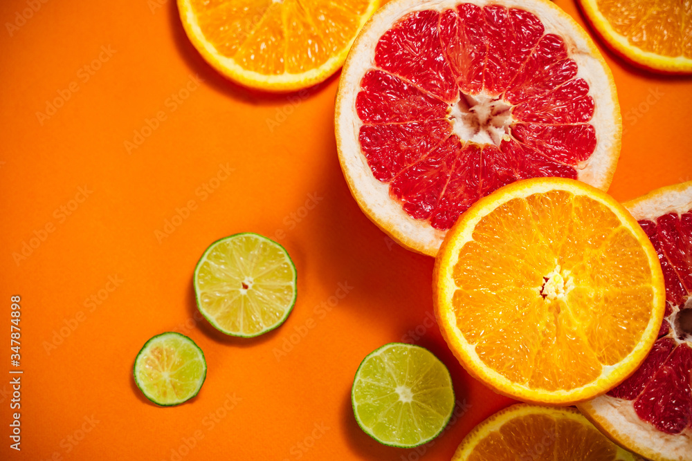Fresh slices of citrus on the orange background. View from above. Place for text. Fresh slices of citrus on the orange background. View from above. Place for text.