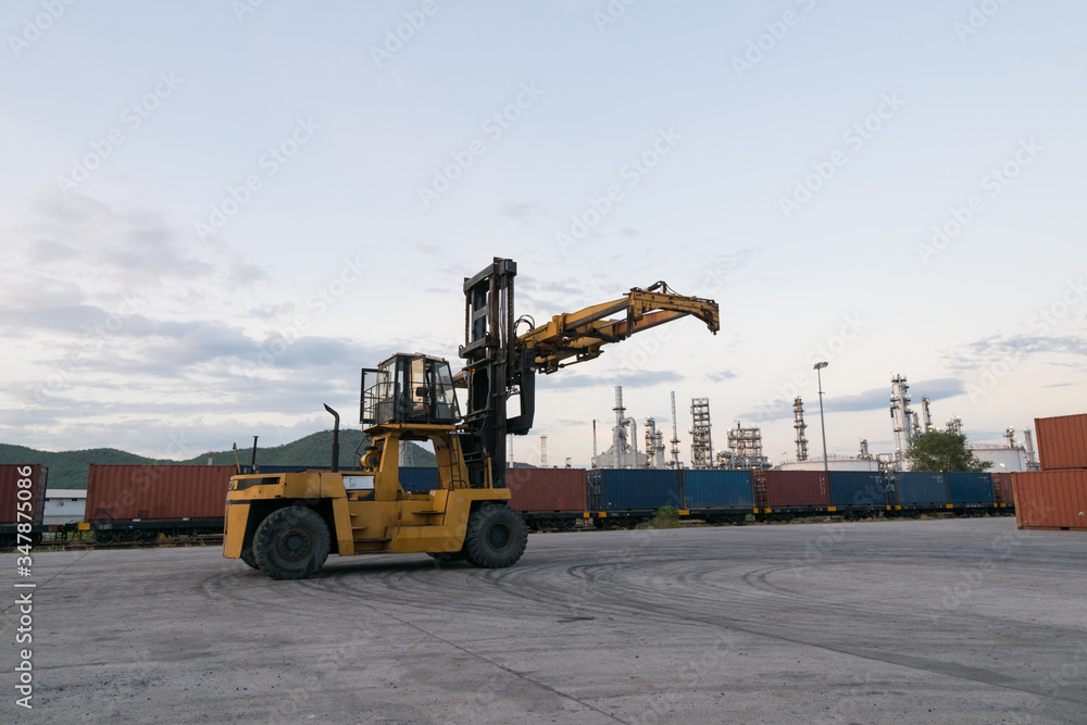 Forklift is waiting handling container box at train station near petrochemical plant Forklift is waiting handling container box at train station near petrochemical plant