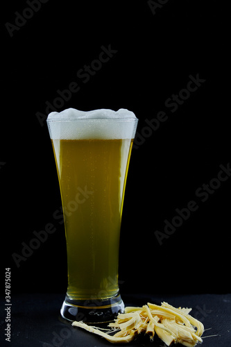Glass of unfiltered wheat beer and suluguni cheese on a black background