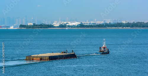 Photography A tug boat pulls a load of sand bound for land reclamation in coastal waterway near Singapore