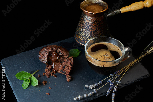 A delicious chocolate muffin, a cup of black coffee, a cezve with custard coffee. Decorated with mint and lavender.