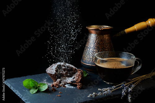 A delicious chocolate muffin, a cup of black coffee, a cezve with custard coffee. Decorated with mint and lavender.