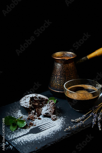 A delicious chocolate muffin, a cup of black coffee, a cezve with custard coffee. Decorated with mint and lavender.