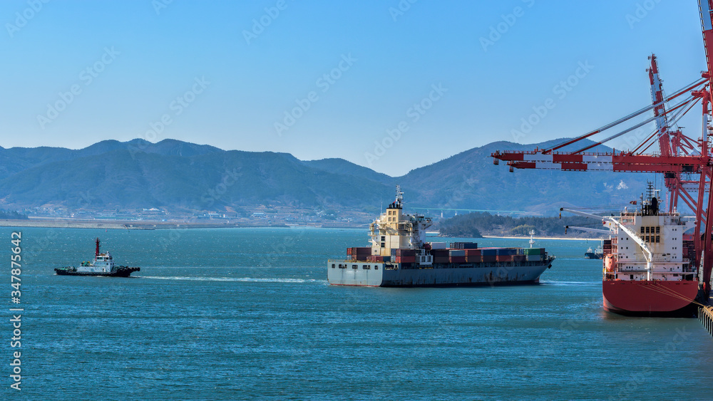 Tugboat assist a container ship on the way out of the harbor.