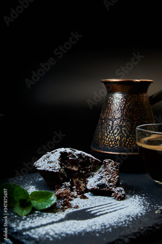 A delicious chocolate muffin, a cup of black coffee, a cezve with custard coffee. Decorated with mint and lavender.