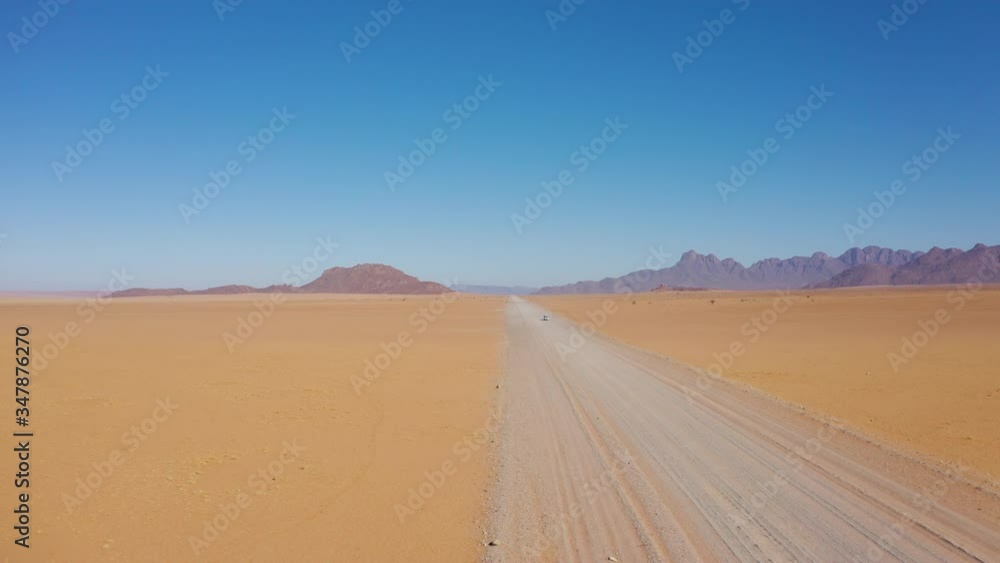 Aerial shot over a 4x4 vehicle driving on a deserted dirt road in the desert in Namibia Aerial shot over a 4x4 vehicle driving on a deserted dirt road in the desert in Namibia
