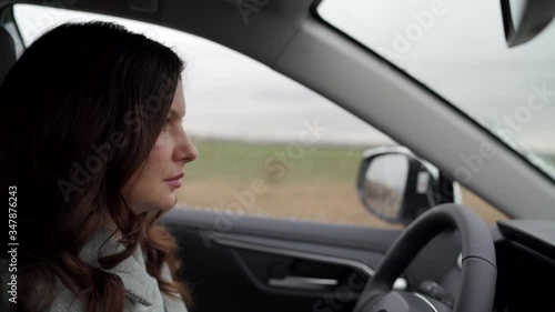 Brunette woman driver behind the steering wheel driving her crossover suv car photo