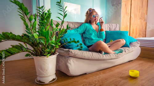 Canvas Print Woman sitting on a sofa smoking sigarette. Self isolation concept