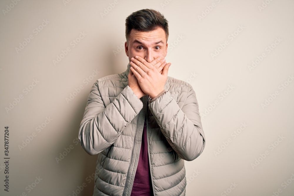 Young handsome caucasian man wearing casual winter jacket standing over isolated background shocked covering mouth with hands for mistake. Secret concept. Young handsome caucasian man wearing casual winter jacket standing over isolated background shocked covering mouth with hands for mistake. Secret concept.