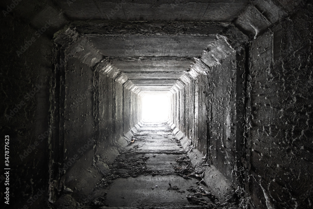 Empty square concrete tunnel with light in the end. Dried culvert.