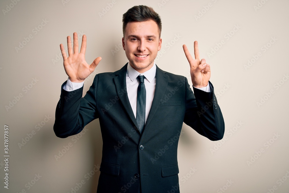Young handsome business man wearing elegant suit and tie over isolated background showing and pointing up with fingers number seven while smiling confident and happy. Young handsome business man wearing elegant suit and tie over isolated background showing and pointing up with fingers number seven while smiling confident and happy.