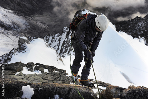 Dramatic view of extreme scene: an alpinist climbs a mountain ridge. Climber ascent to the summit.