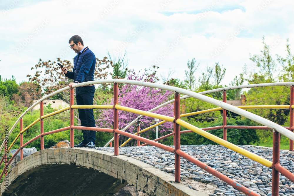 Young businessman sending a text message by mobile phone Young businessman sending a text message by mobile phone