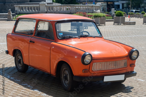 Orange colored vintage restored Trabant car on paved street