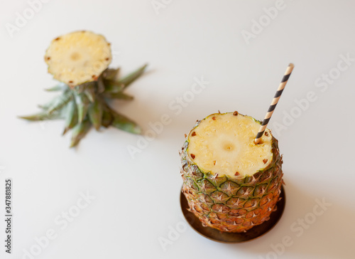 feed on top, ripe anance with a cut off top and a straw, on a white table photo