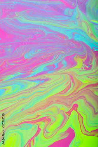 Colorful marble background.Mixed nail polishes-yellow,pink,blue.Colorful marble background.Beautiful stains of liquid nail polish,fluid art technique.Pour painting technique.Vertical banner.