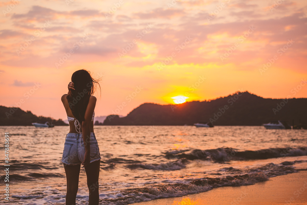 Traveler woman walking on beach in sunset Traveler woman walking on beach in sunset