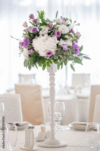 Wedding table decorated on mauve color. Centerpiece full of violet flowers in the middle © Mihai