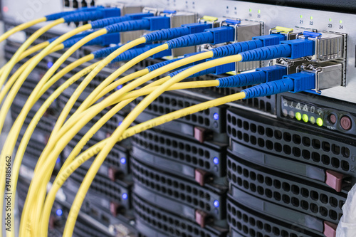 A bunch of fiber-optic Internet wires are connected to the router modules. Yellow telecommunications cable in the server room of the data center. Concept of fast broadband access to the network
