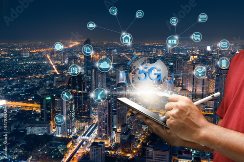 Man's hand holding a tablet with a pen and technology icons. Smart intelligent city and wireless 5G network and the Internet to high-speed data communication