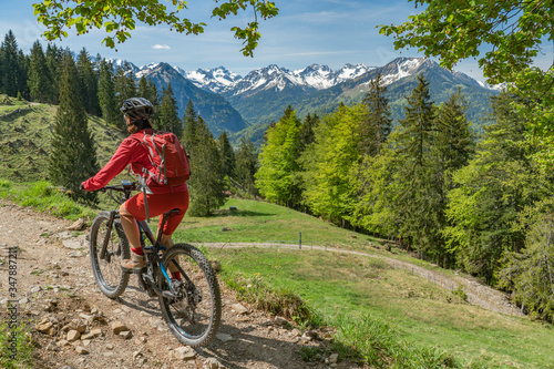 pretty senior woman riding her electric mountain bike on the Wallraff Trail in the Nebelhorn area above Oberstdorf, Allgau Alps, Bavaria, 