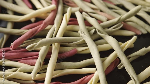 Traditional raw Italian fileja pasta of various colors dropping in batches into a pile. Closeup shot