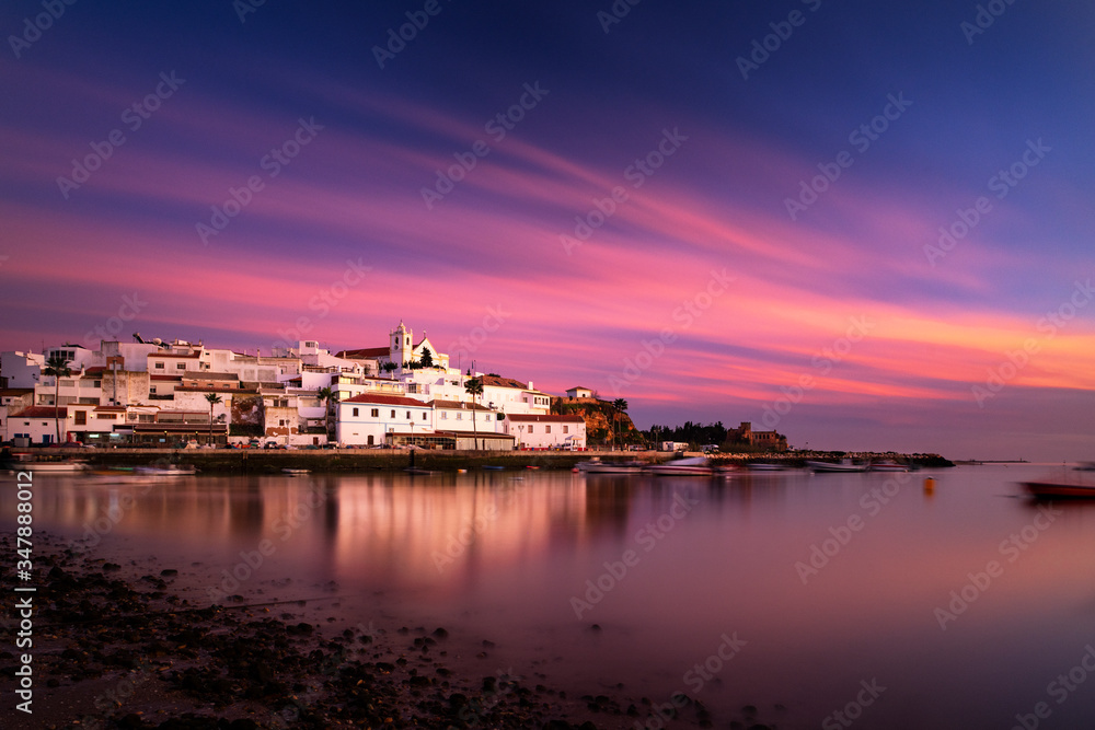 Beautiful view of the traditional village of Ferragudo in Lagoa, Algarve, at sunset, with the traditional houses and boats at the fishing port. Beautiful view of the traditional village of Ferragudo in Lagoa, Algarve, at sunset, with the traditional houses and boats at the fishing port.