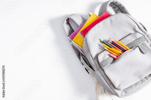 Back to school concept. Backpack with school supplies, pens, pencils, notebook on white background. Flat lay, top view, copy space photo