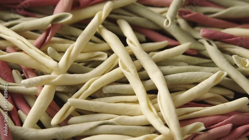 Pile of traditional raw Italian fileja pasta of various colors fast spin. Macro shot