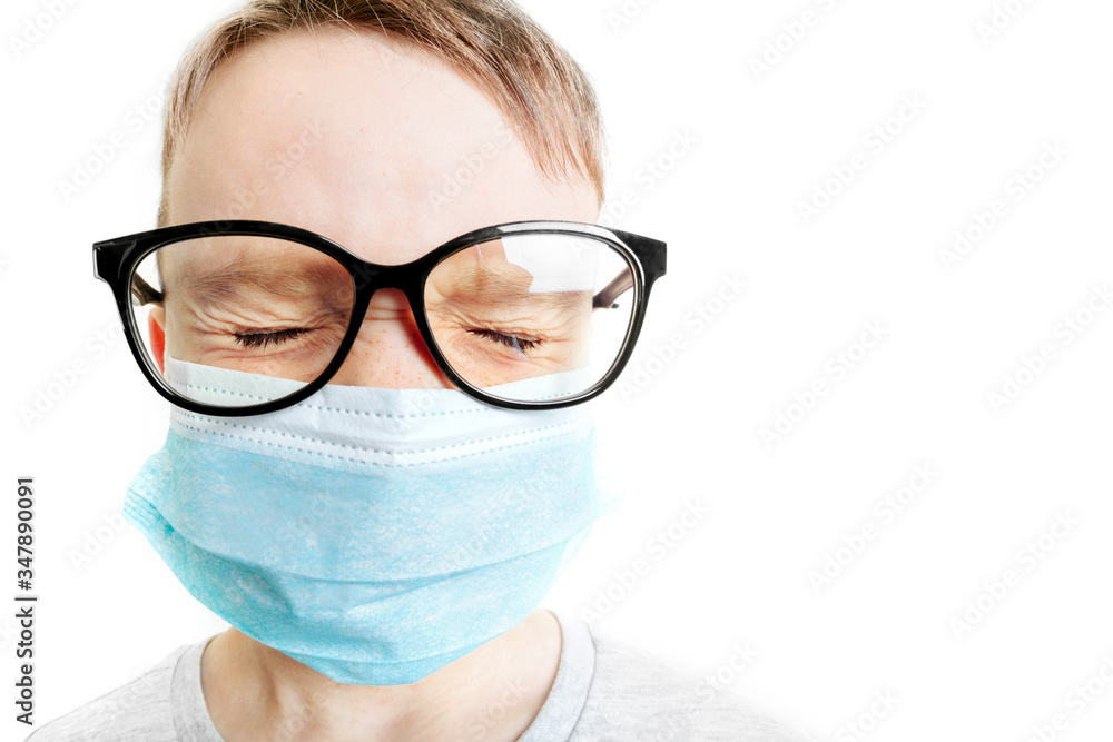 Face of a mask-wearing boy with fear in the eye Close-up on a gray background.Coronavirus and Air pollution pm2.5 concept. COVID-19 Face of a mask-wearing boy with fear in the eye Close-up on a gray background.Coronavirus and Air pollution pm2.5 concept. COVID-19