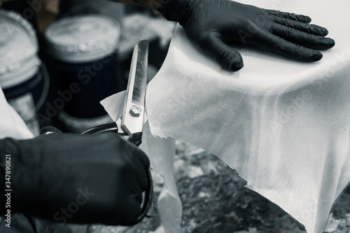Foto Manufacturing process of a surfboard by a white shirt shaper and black gloves inside his workshop