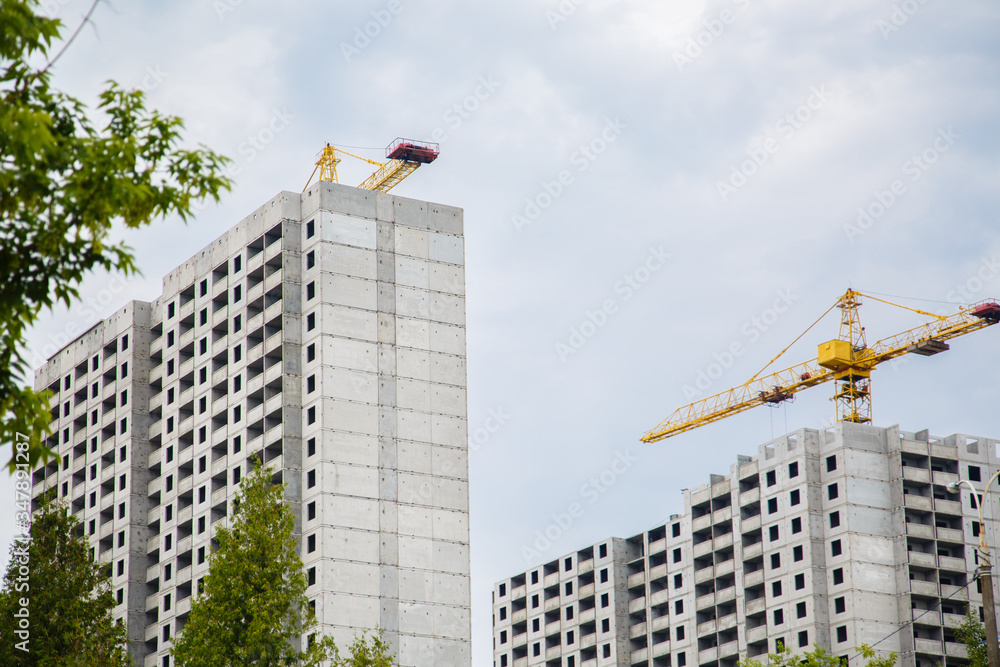 construction of iron-concrete high-rise building. Construction workplace in the summer. Details of unfinished building on the construction site. The erection of a new residential multi-storey house construction of iron-concrete high-rise building. Construction workplace in the summer. Details of unfinished building on the construction site. The erection of a new residential multi-storey house