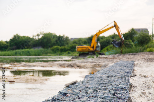 excavator is working on the site. Strengthening the coastline with a stone border. Sand and gravel. Construction works with bulldozer. Selective focus