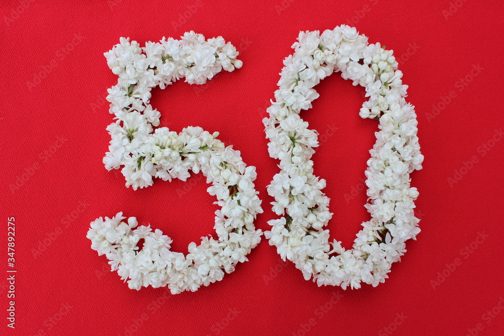 The number 50 is written in white lilac flowers on a red background. The number fifty is written in fresh flowers, isolated on red. Arabic numeral lined with flowers.