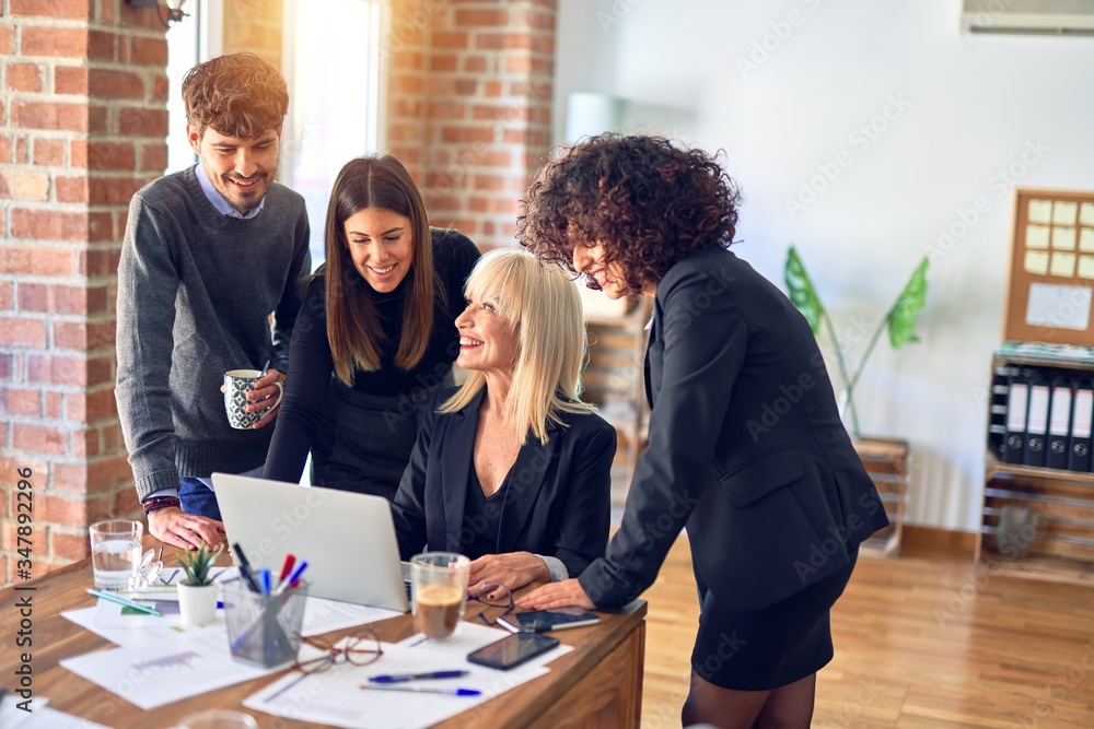Group of business workers smiling happy and confident. Working together with smile on face using laptop at the office Group of business workers smiling happy and confident. Working together with smile on face using laptop at the office