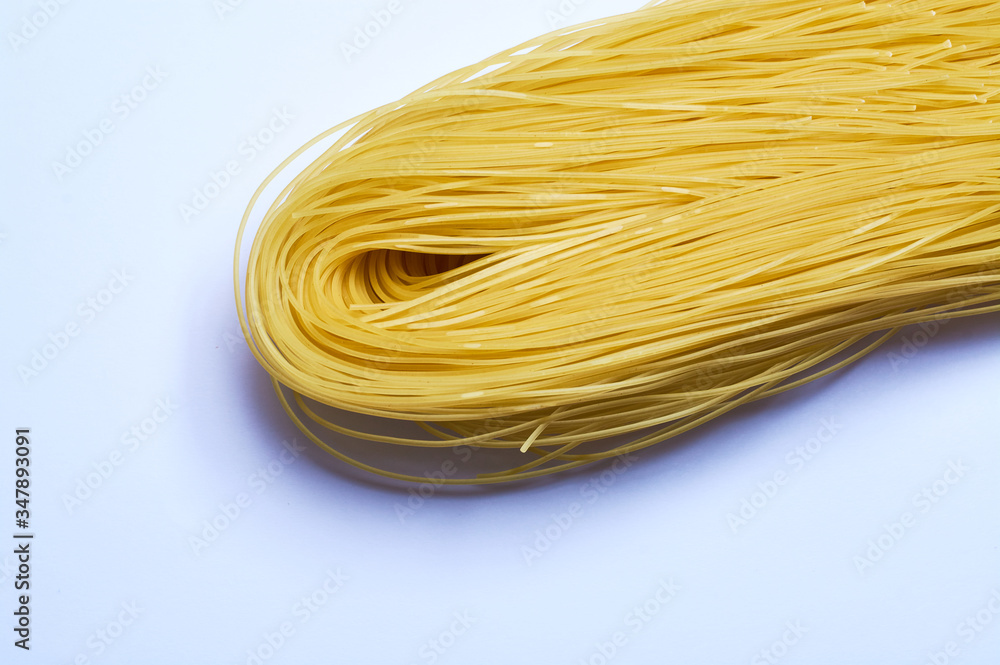 White background and thin Italian noodles, spaghetti, pasta of wheat, raw. White background and thin Italian noodles, spaghetti, pasta of wheat, raw.