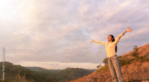 Enjoying the nature.Young beautiful woman arms raised relax and feeling good the fresh air in tropical forest at sunset. Freedom concept.