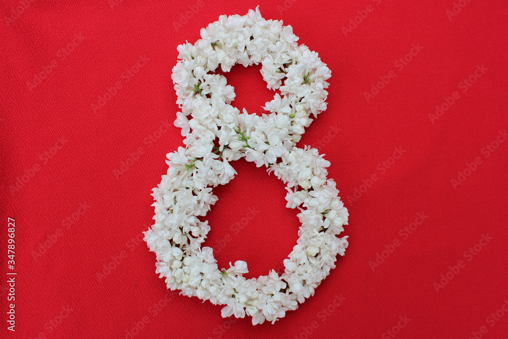 The number 8 is written in white lilac flowers on a red background. The number eight is written in fresh flowers, isolated on red. Arabic numeral lined with flowers.