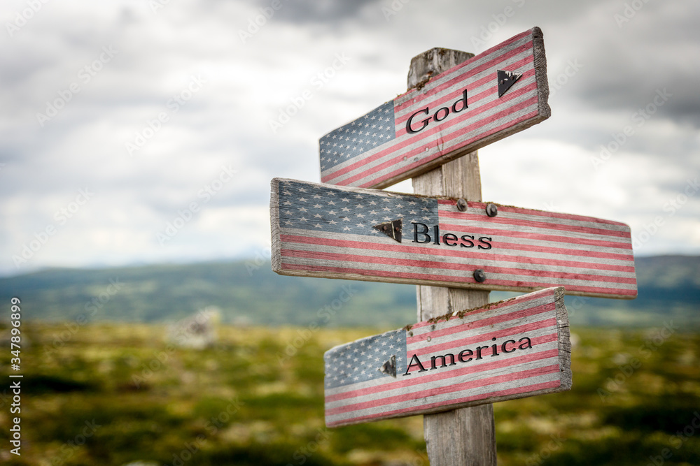 God bless america text on wooden american flag signpost outdoors in nature.