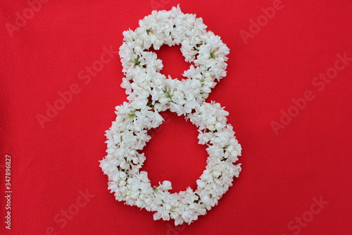 Obraz na płótnie The number 8 is written in white lilac flowers on a red background. The number eight is written in fresh flowers, isolated on red. Arabic numeral lined with flowers. w salonie