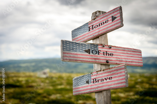 home of the brave text on wooden american flag signpost outdoors in nature. © Jon Anders Wiken